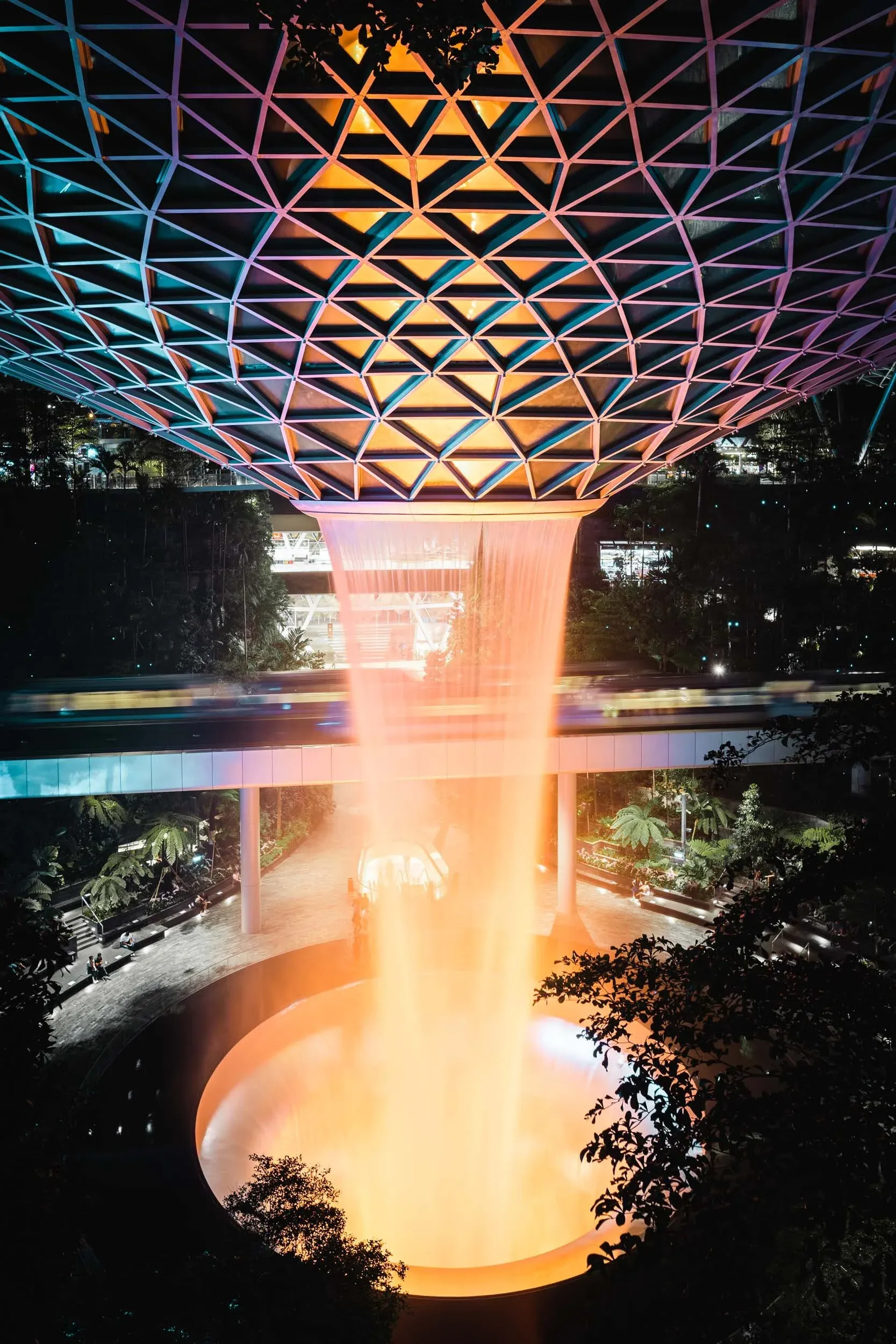 The fountain in the middle of the Jewel is surrounded by an indoor garden and mall. The terminal trains pass through the Jewel on a bridge.